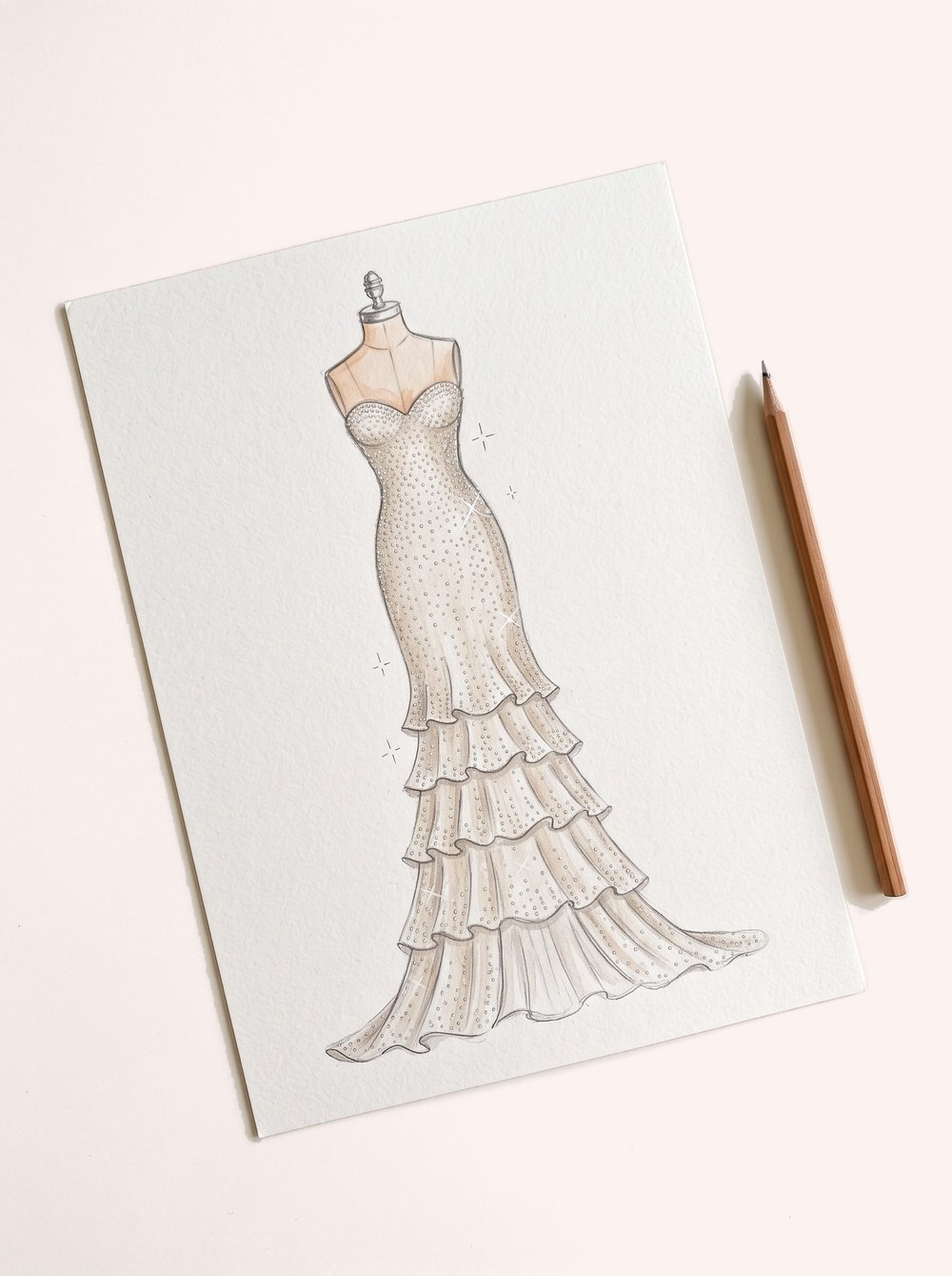 Pencil sketch of a beaded gown on a sheet of paper with a pencil beside it